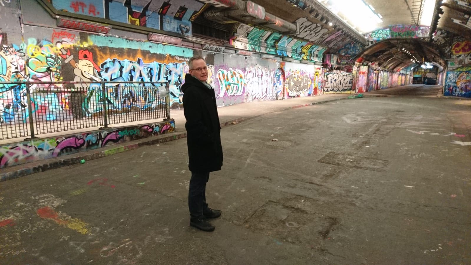 Canon Giles Goddard in the Leak Street tunnel covered in colourful graffiti